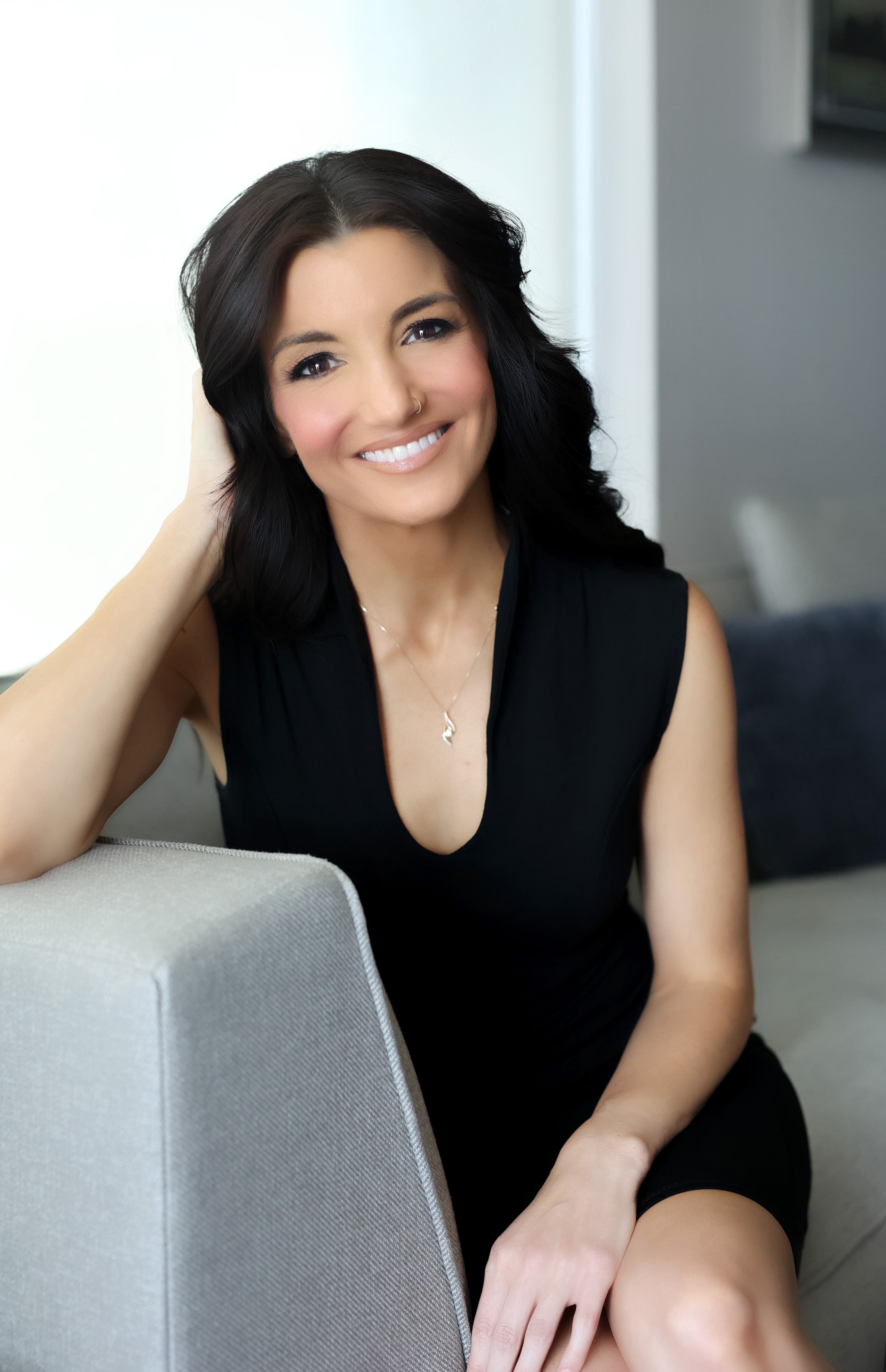 A woman in a black dress sitting on a couch