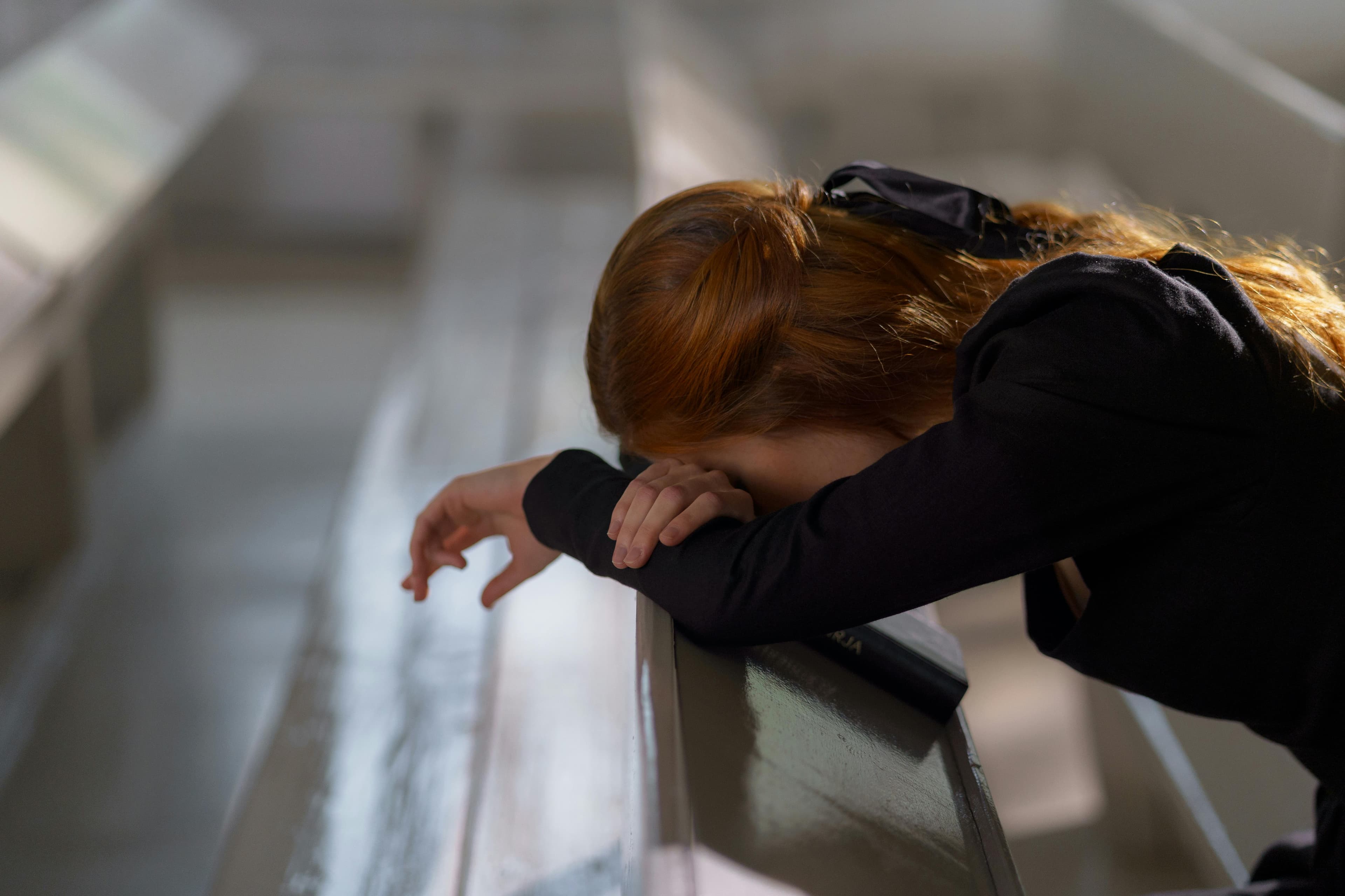 A woman leaning her head on a bench