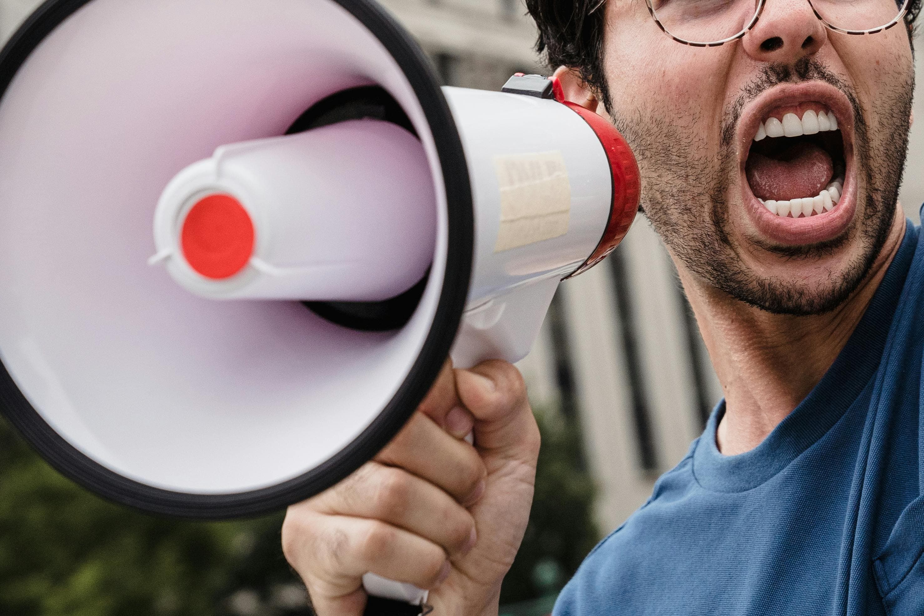 A man shouting into a megaphone with his mouth wide open